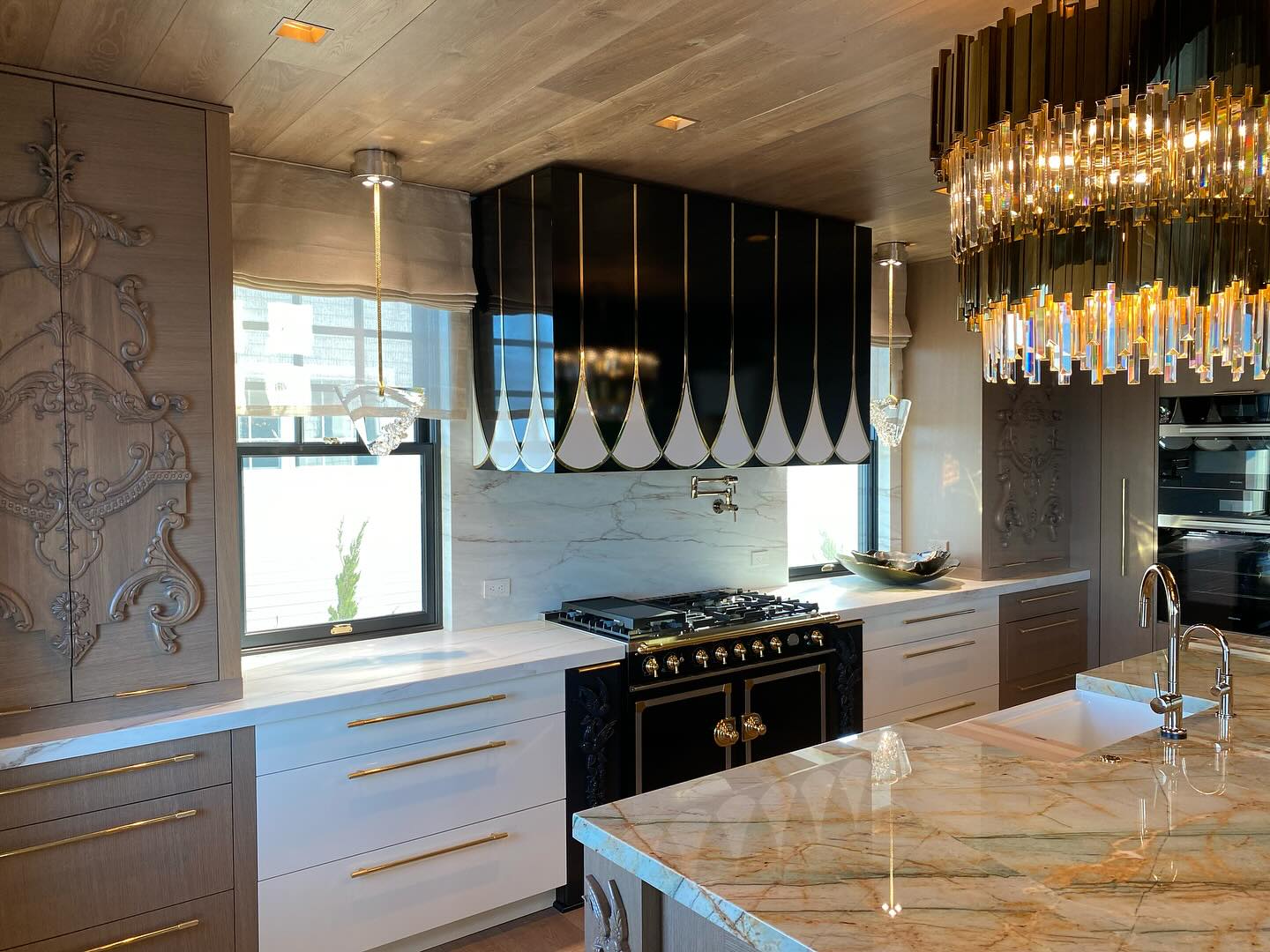 Luxury custom kitchen in Ocean City, NJ with a black and brass range hood and marble island